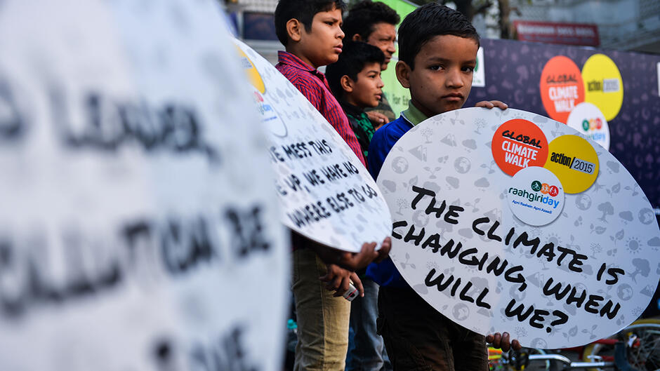 Un jeune Indien qui tient une pancarte en forme d’appel : « le climat change, quand changerons-nous ? »