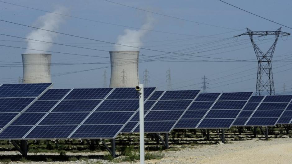 Image de panneaux photovoltaïques devant les tours de refroidissement de la centrale nucléaire du Tricastin, en Provence