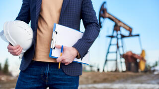 An inspector in oil field holding folder for notes