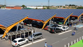 A photo of a supermarket in the south of France. Its parking lot is sheltered by canopies with solar PV panels.