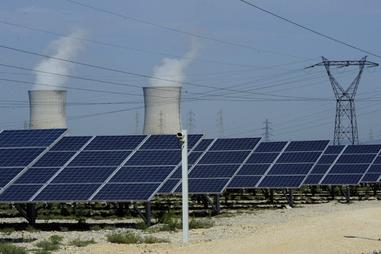 Image de panneaux photovoltaïques devant les tours de refroidissement de la centrale nucléaire du Tricastin, en Provence